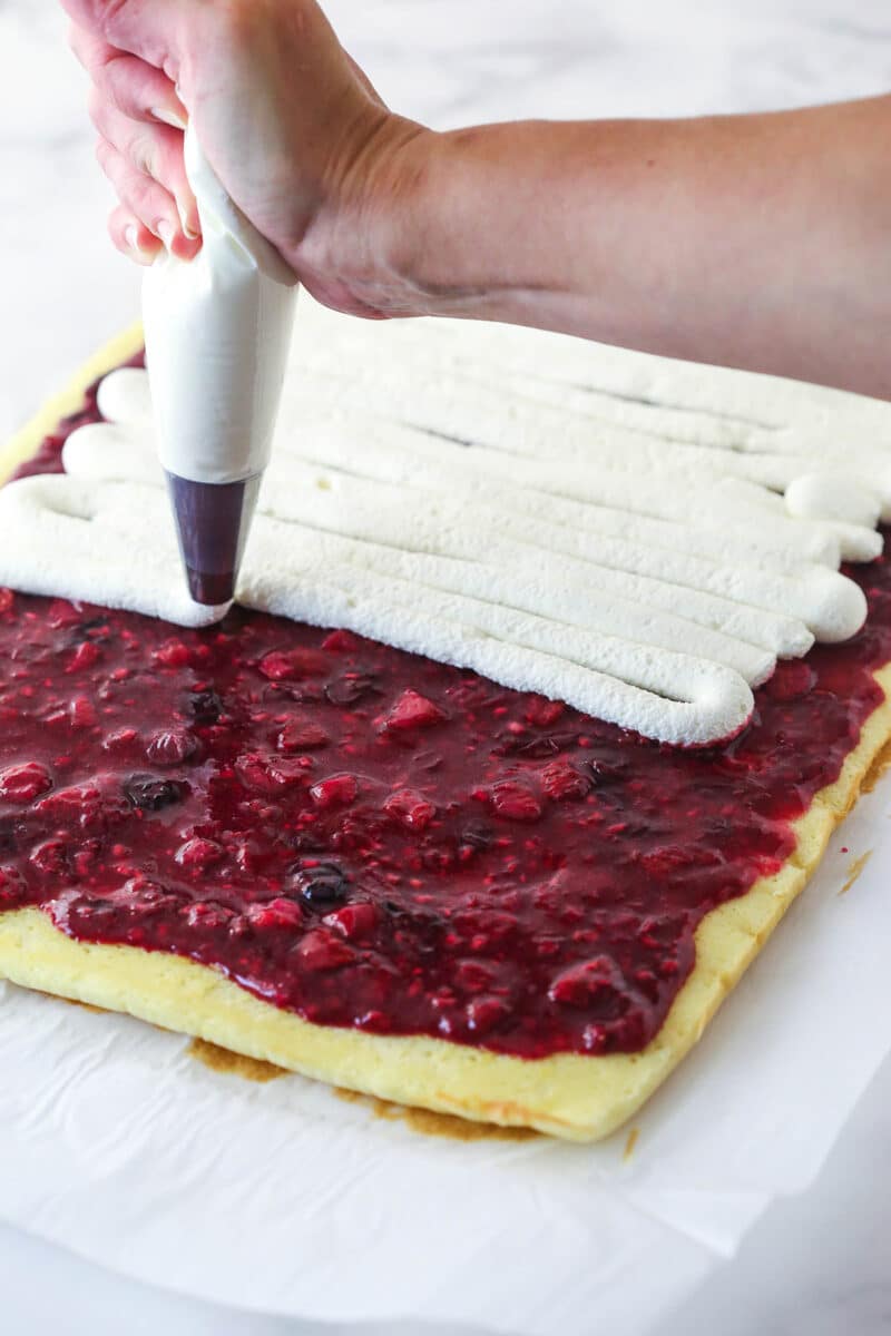 piping the whipped cream filling on top of the berry filling