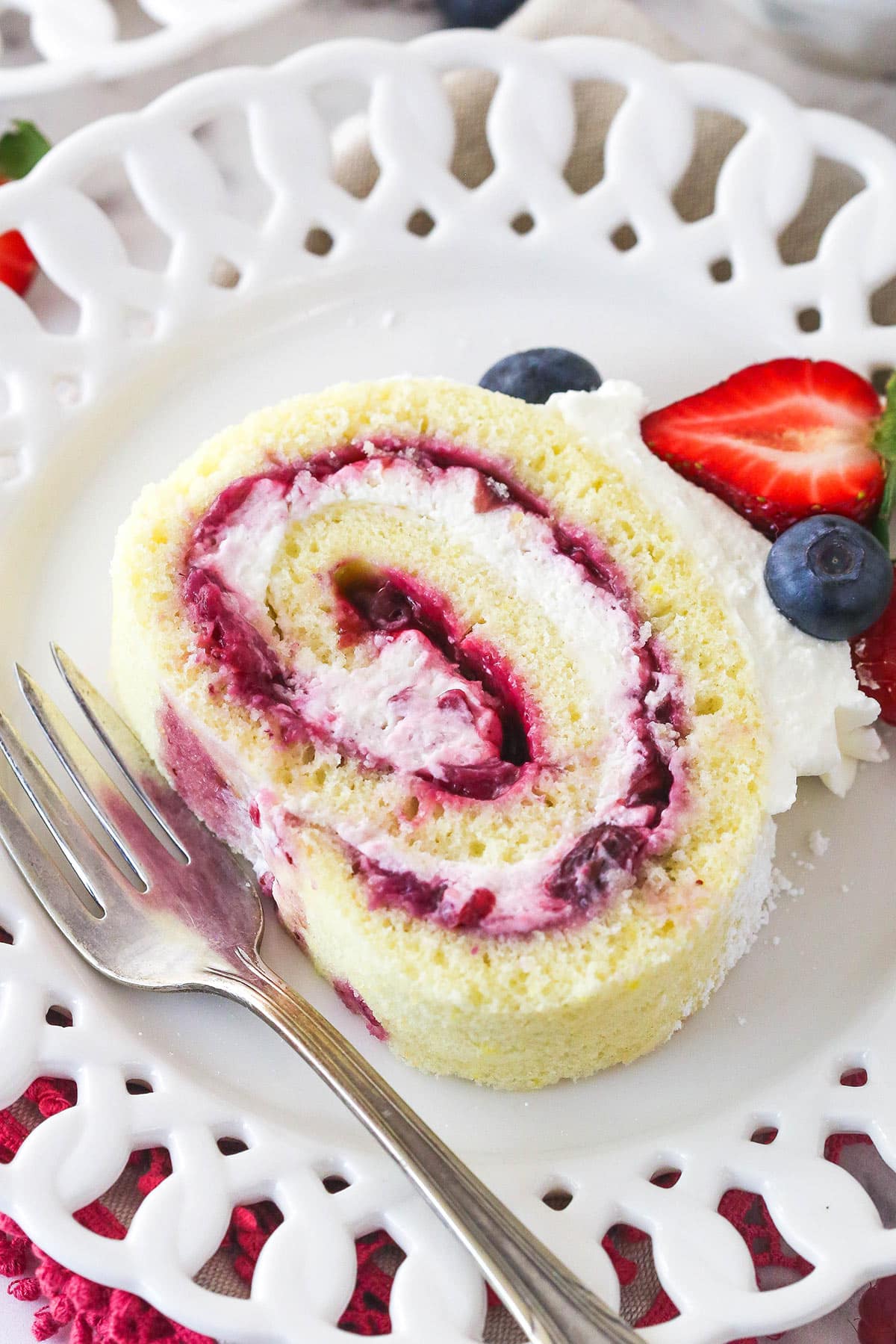 Berry Vanilla Cake Roll slice on a white plate with a fork