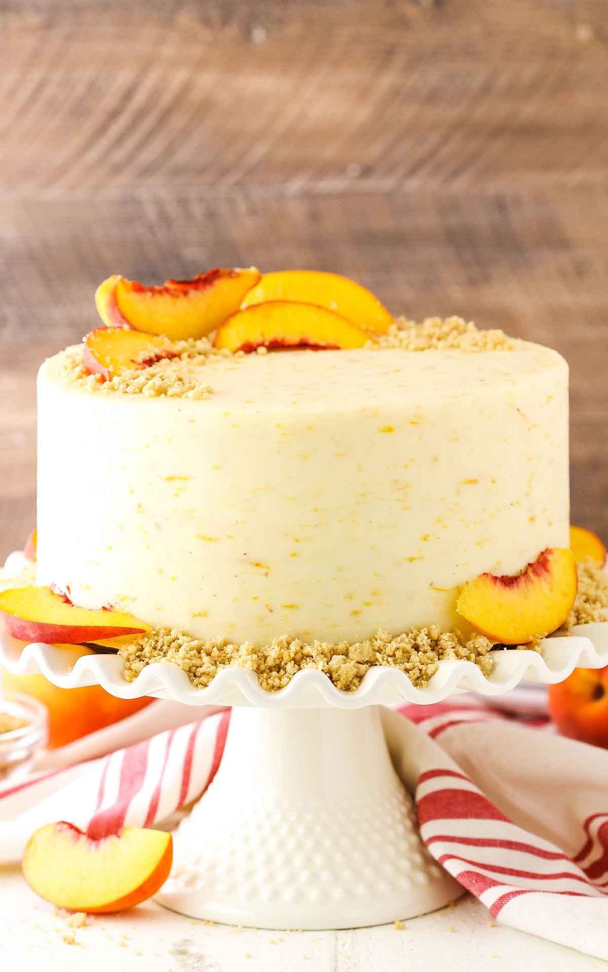 A full Brown Sugar Layer Cake With Peach Filling on a white cake stand