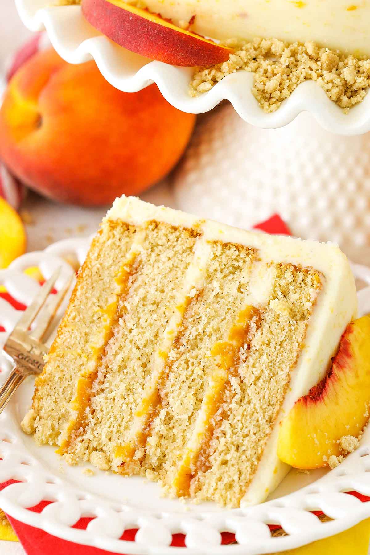 A slice of Brown Sugar Layer Cake With Peach Filling next to a silver fork on a white plate