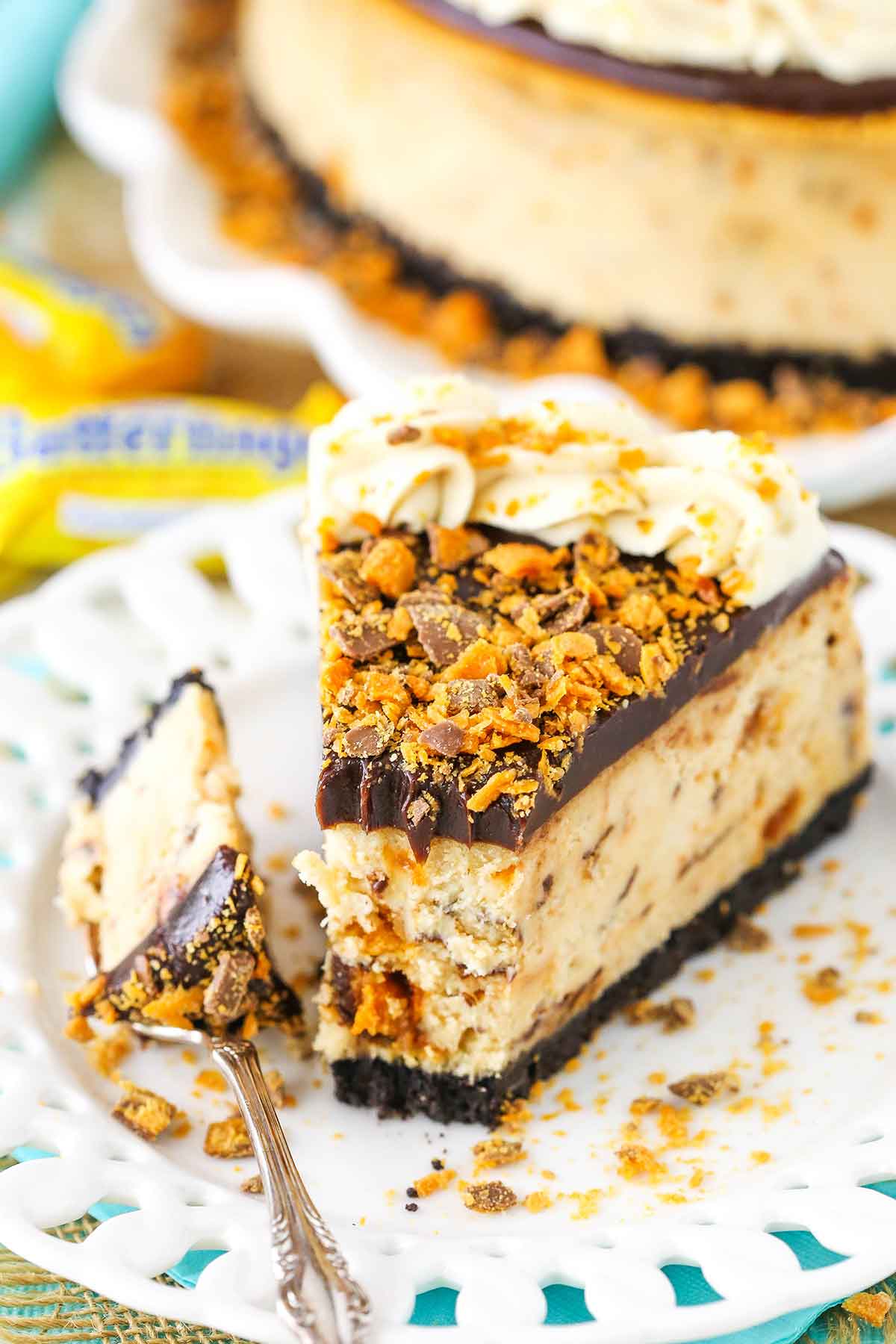A slice of Butterfinger Cheesecake with a bite removed on a white plate