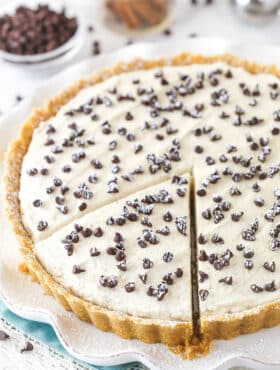 Cannoli tart on a serving platter with a slice cut and ready to serve.