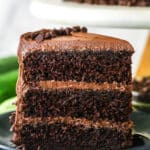 A slice of chocolate zucchini cake upright on a plate.