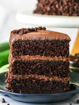 A slice of chocolate zucchini cake upright on a plate.