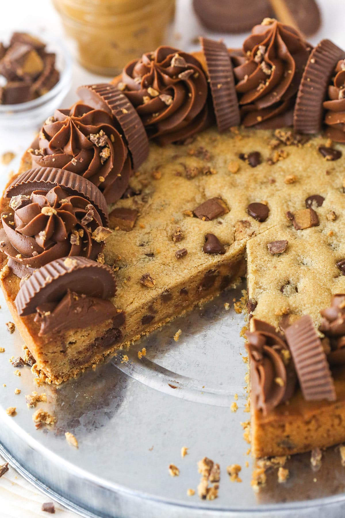 Reese's peanut butter cookie cake on a serving plate with a slice taken out of it.