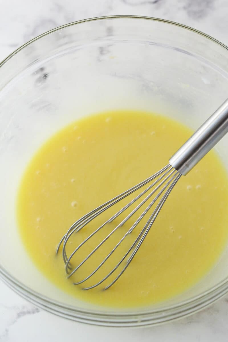 Whisking lemon juice and milk into the wet ingredients for strawberry bread.