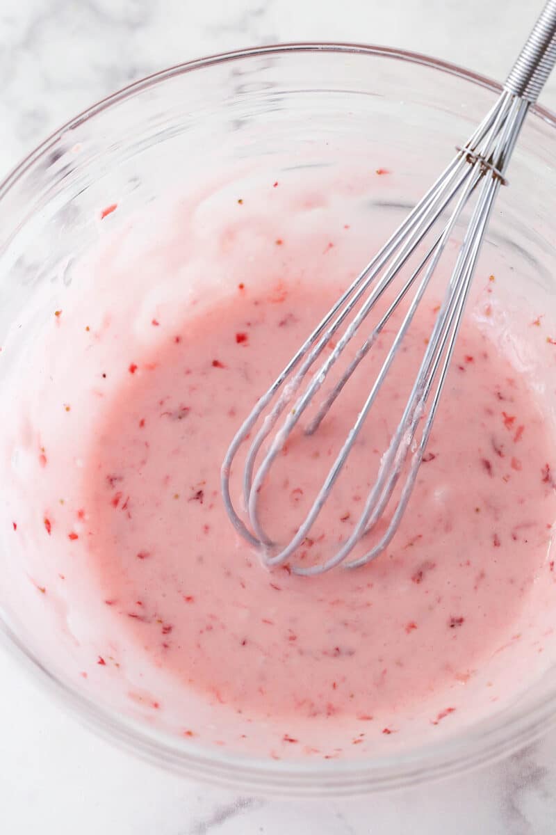 Whisking together strawberry glaze in a mixing bowl.