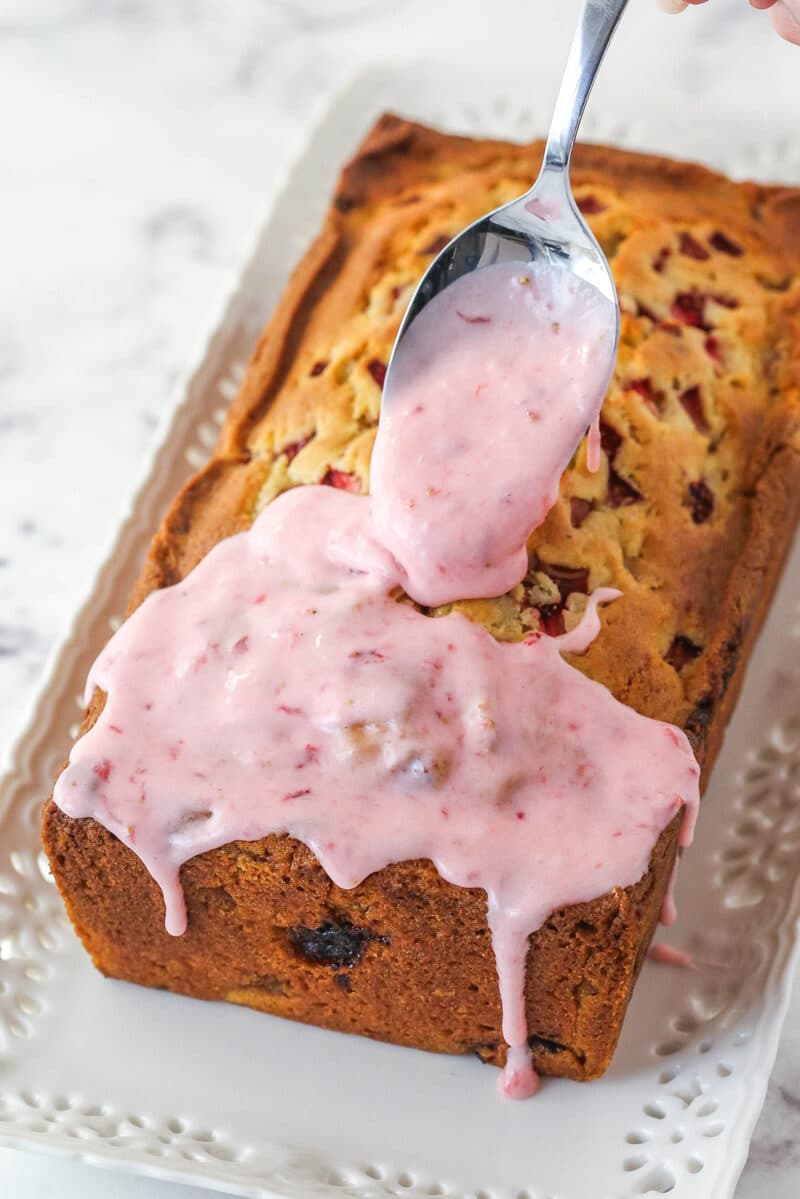 Pouring strawberry glaze over strawberry bread.