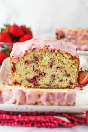 Strawberry bread on a serving platter with a slice cut out of it.