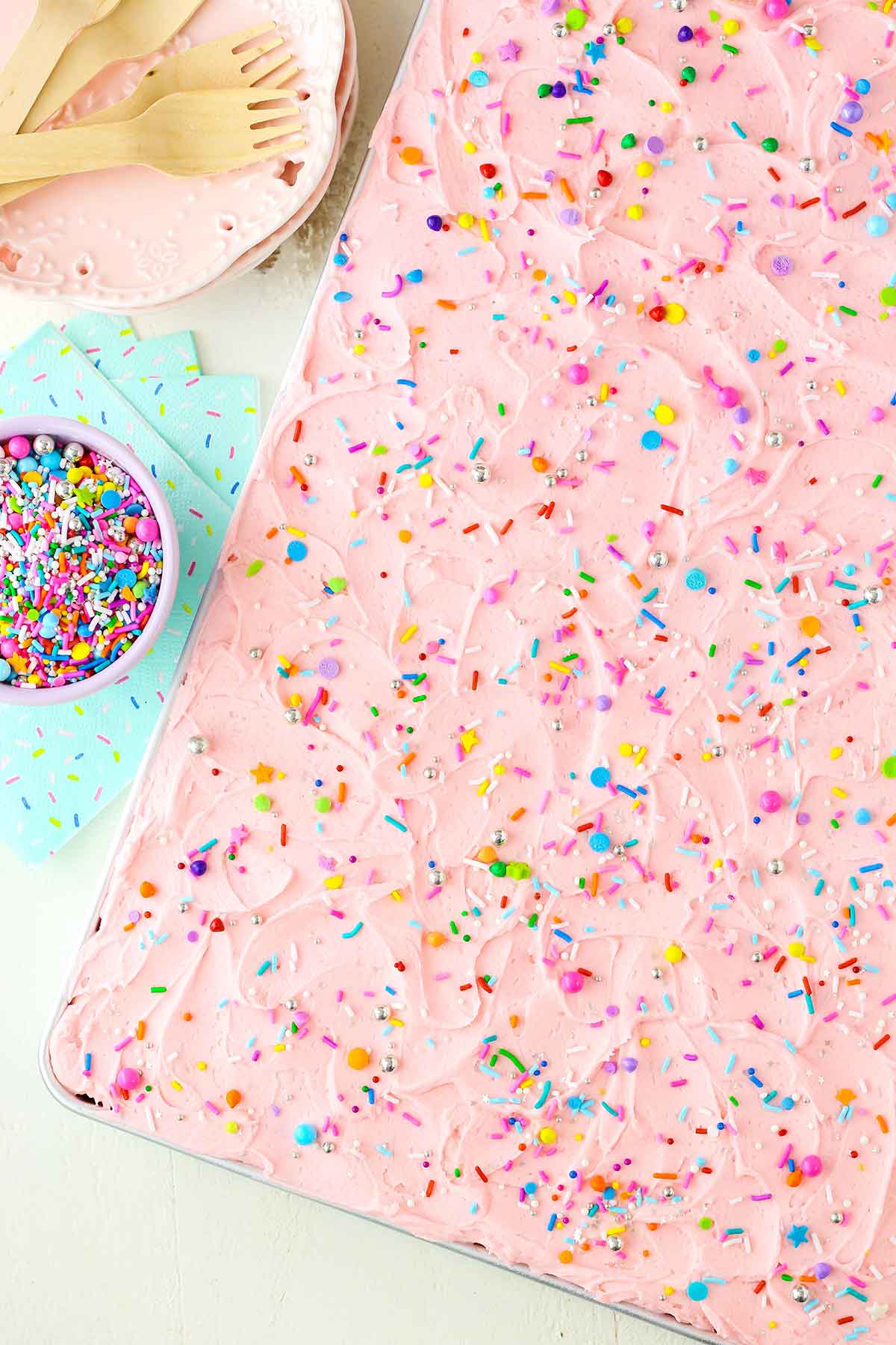 Overhead view of a full Vanilla Sheet Cake next to a bowl of sprinkles