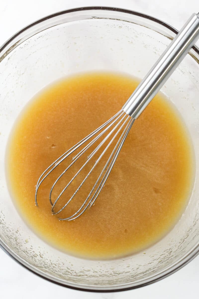 Whisking together melted butter, vegetable oil, sugars, eggs, vanilla, and applesauce.