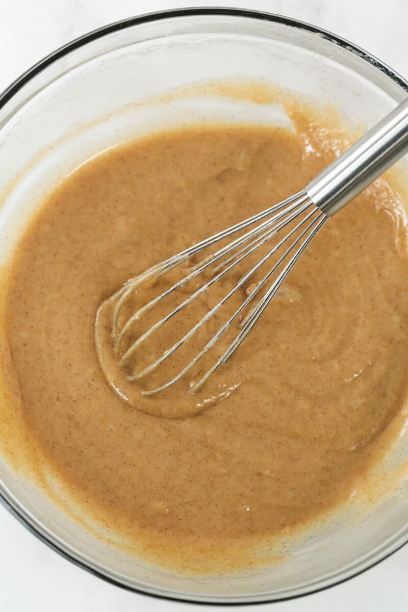 Whisking the dry ingredients into zucchini bread batter.