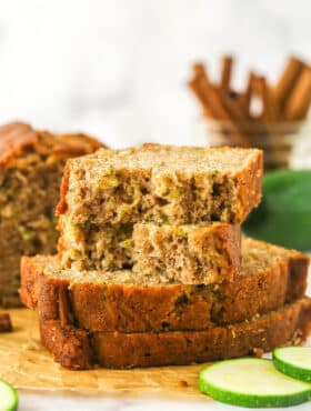 Sliced of zucchini bread stacked on top of each other. The top slice is torn in half.