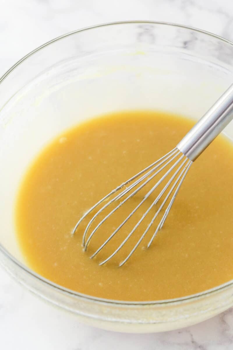 Mixing eggs and sour cream into a mixture of butter, vegetable oil, sugars, and vanilla