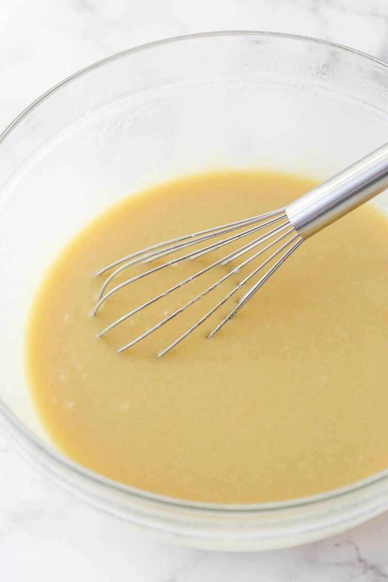 Whisking milk into the wet ingredients for cake batter.