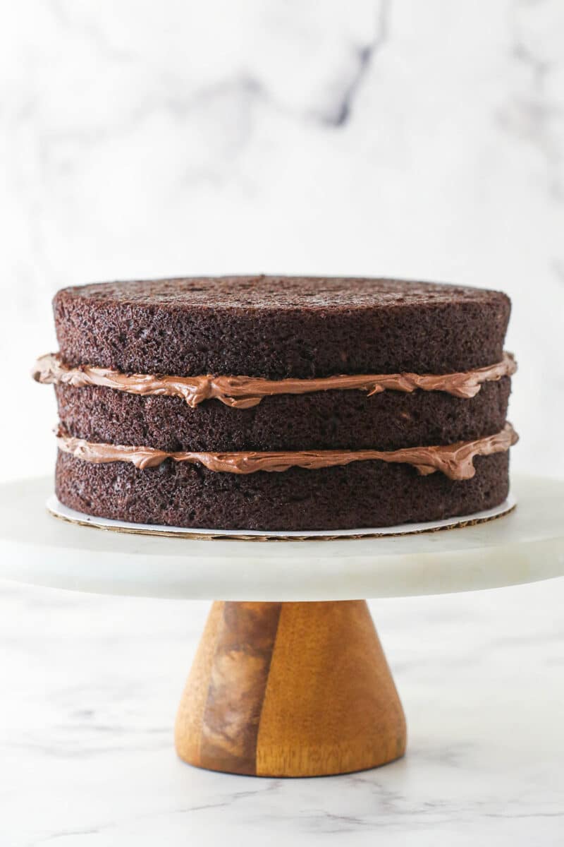 Stacking and filling chocolate zucchini layer cake.