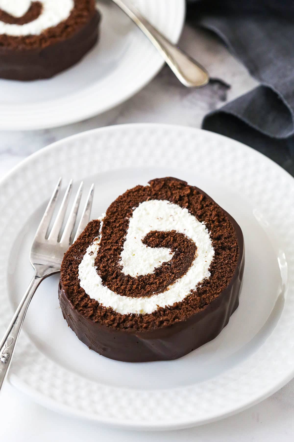 A slice of chocolate Swiss roll on a white plate