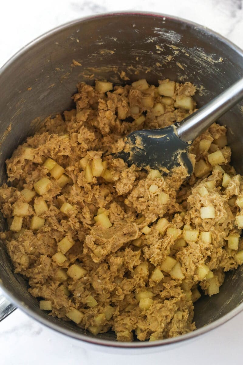 Apple cinnamon oatmeal cookie dough in a mixing bowl with a spatula.