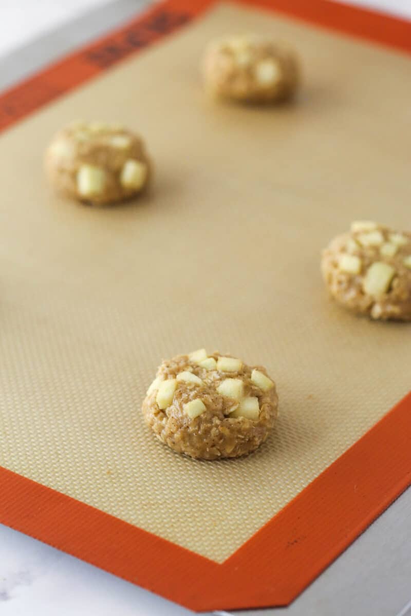 Unbaked apple cookie dough balls on a baking mat.