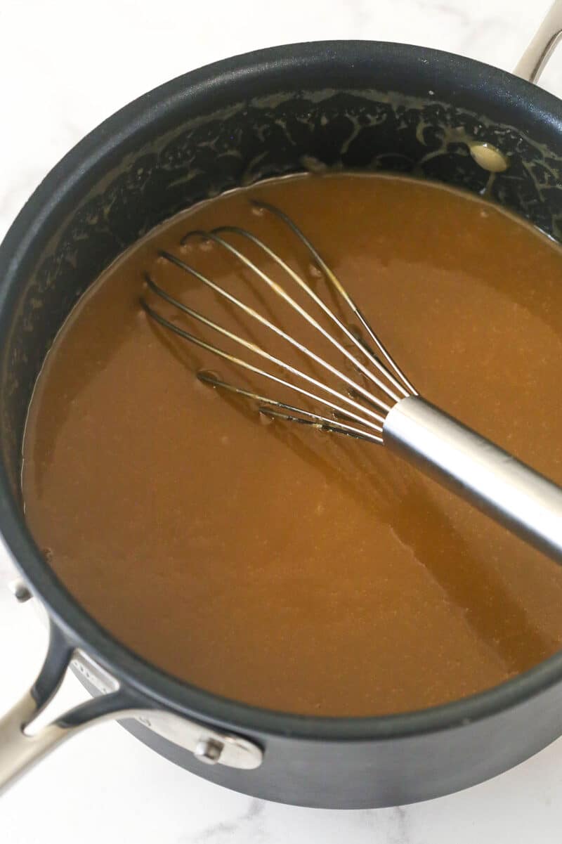 A pot with thin caramel and whisk.