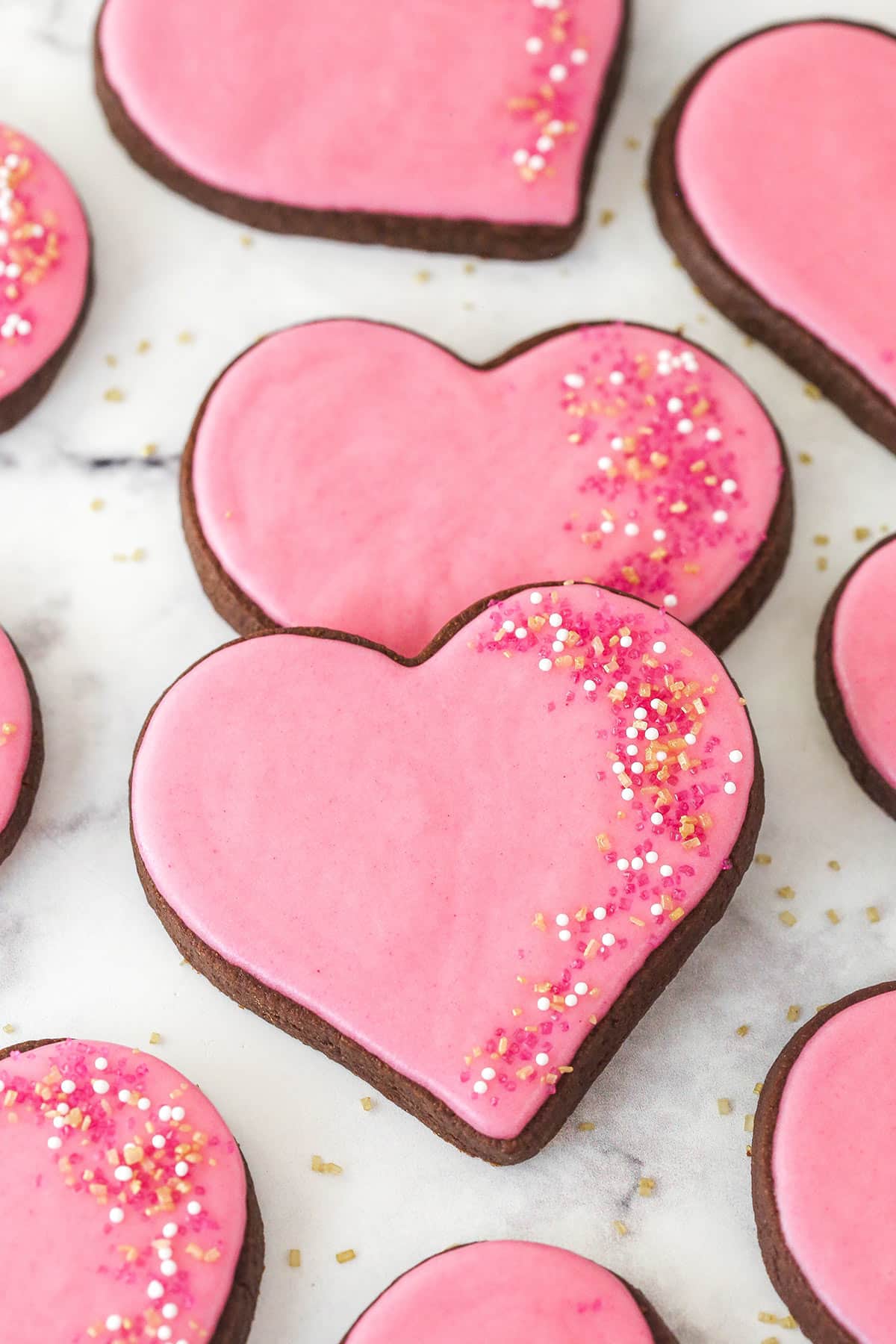 Two chocolate cutout cookies decorated with pink icing