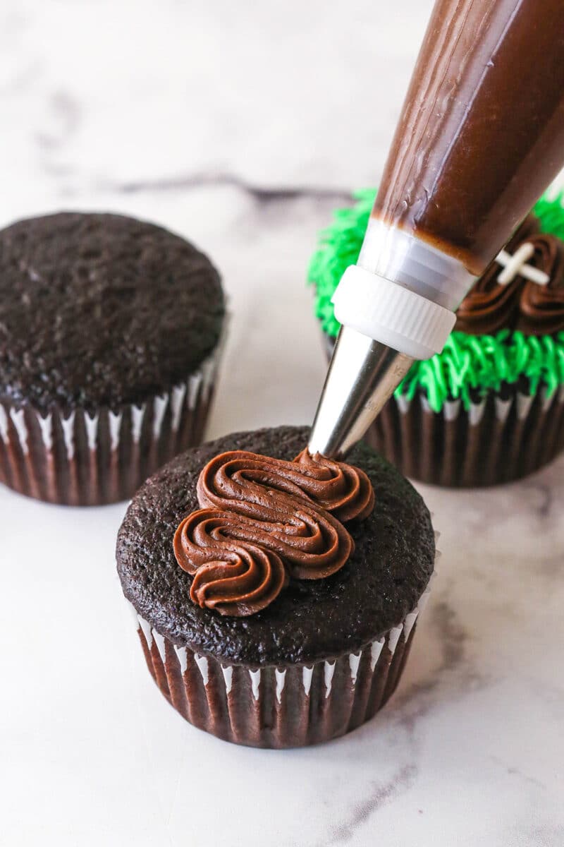 piping chocolate buttercream football onto cupcakes