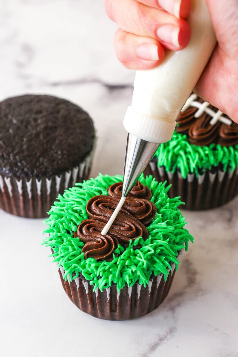 piping white laces onto football cupcake