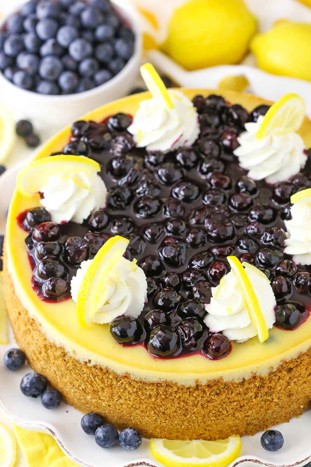 Overhead view of a full Lemon Blueberry Cheesecake on a white cake stand