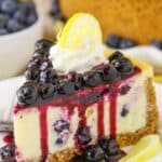 Side view of a slice of Lemon Blueberry Cheesecake on a white plate