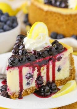 Side view of a slice of Lemon Blueberry Cheesecake on a white plate