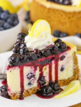 Side view of a slice of Lemon Blueberry Cheesecake on a white plate