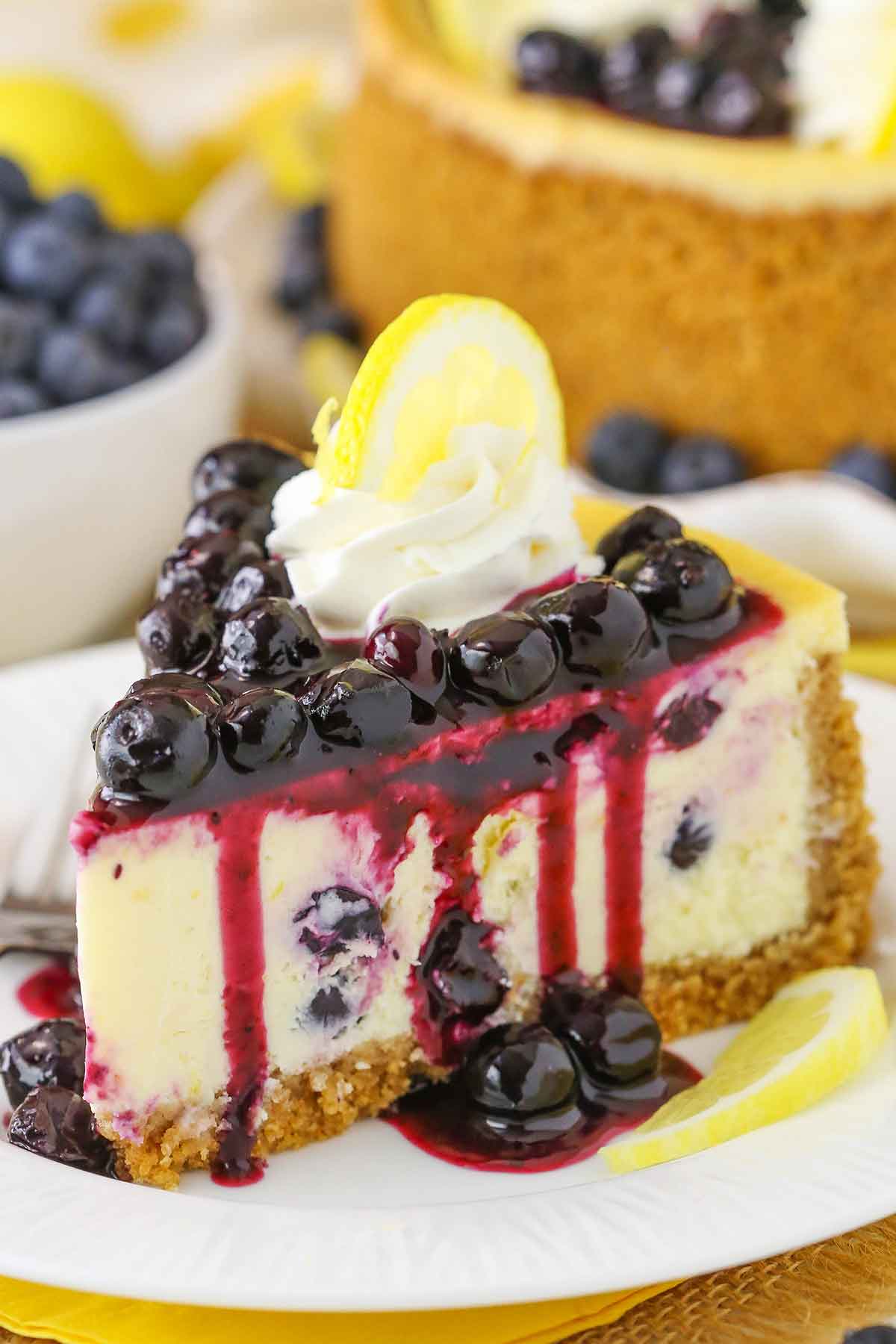 Side view of a slice of Lemon Blueberry Cheesecake on a white plate