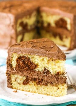 A slice of Marble Cake next to a fork on a white plate