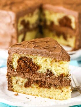 A slice of Marble Cake next to a fork on a white plate