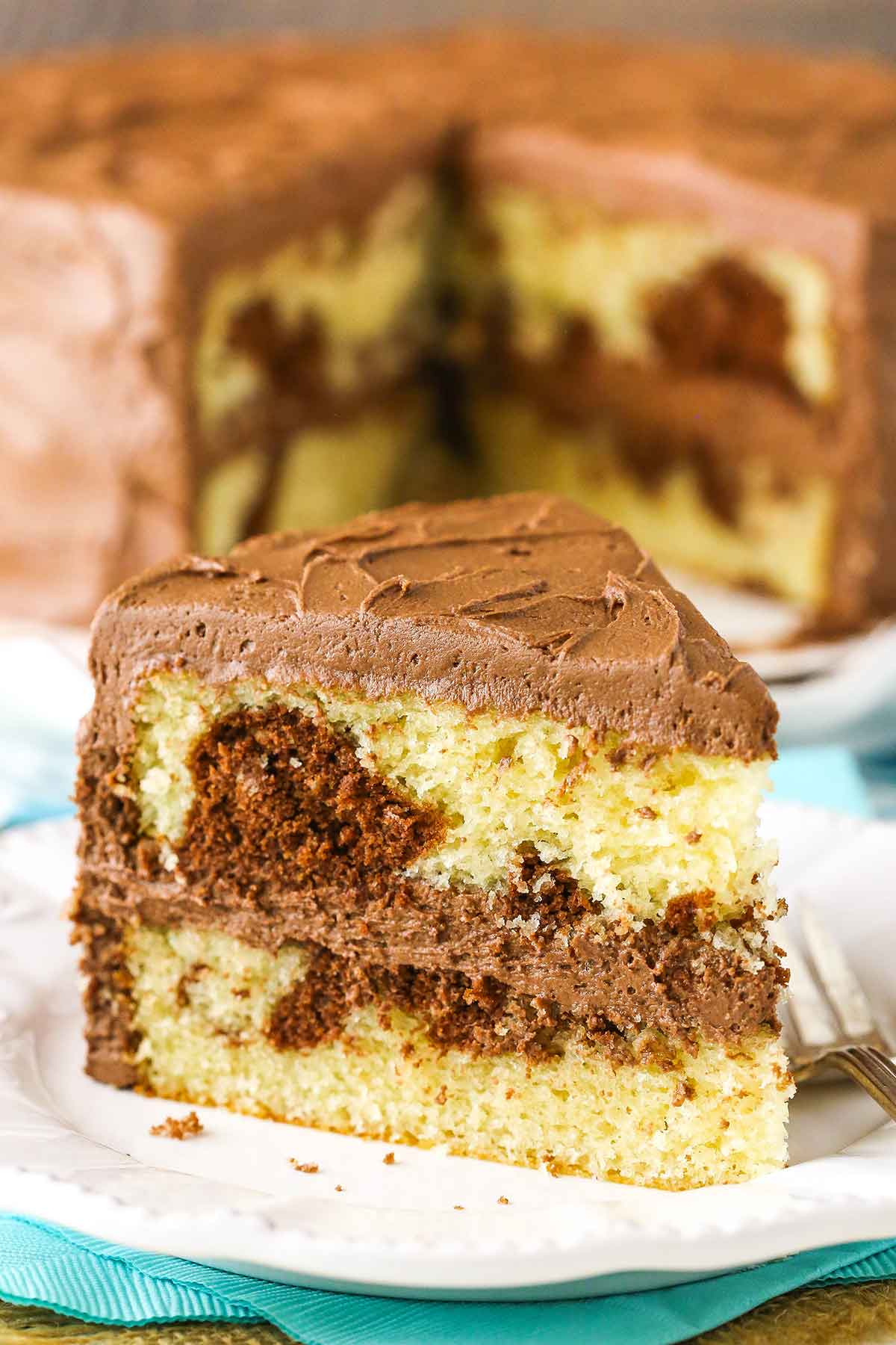 A slice of Marble Cake next to a fork on a white plate