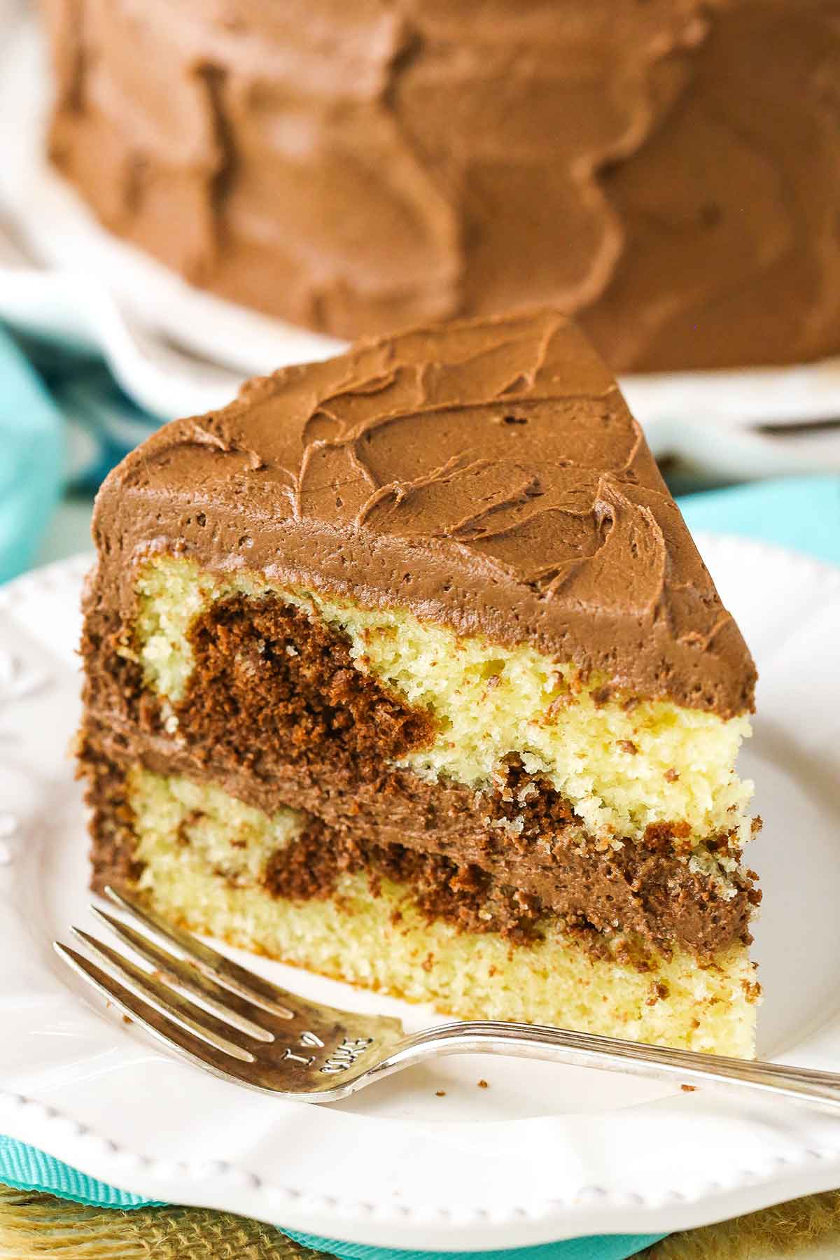 A slice of Marble Cake next to a fork on a white plate