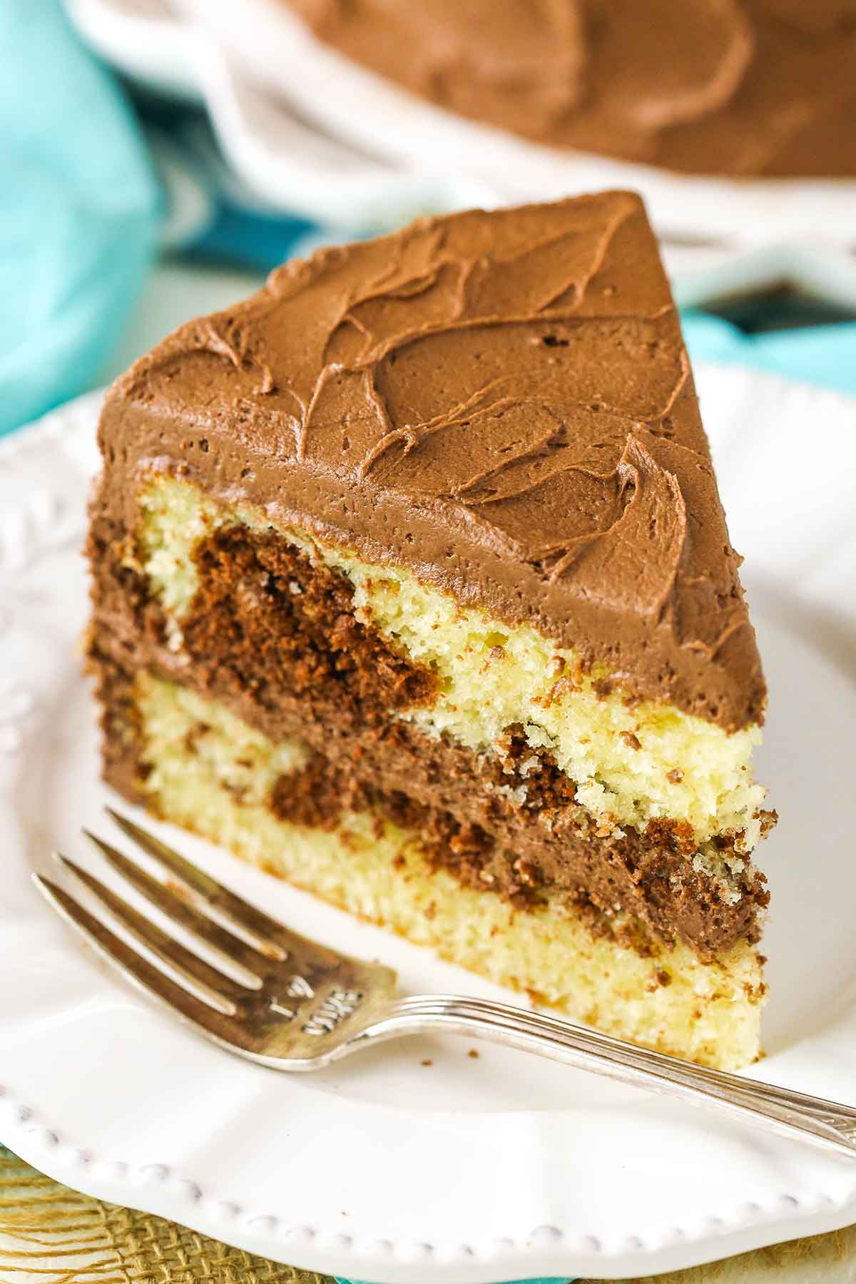 A slice of Marble Cake next to a fork on a white plate