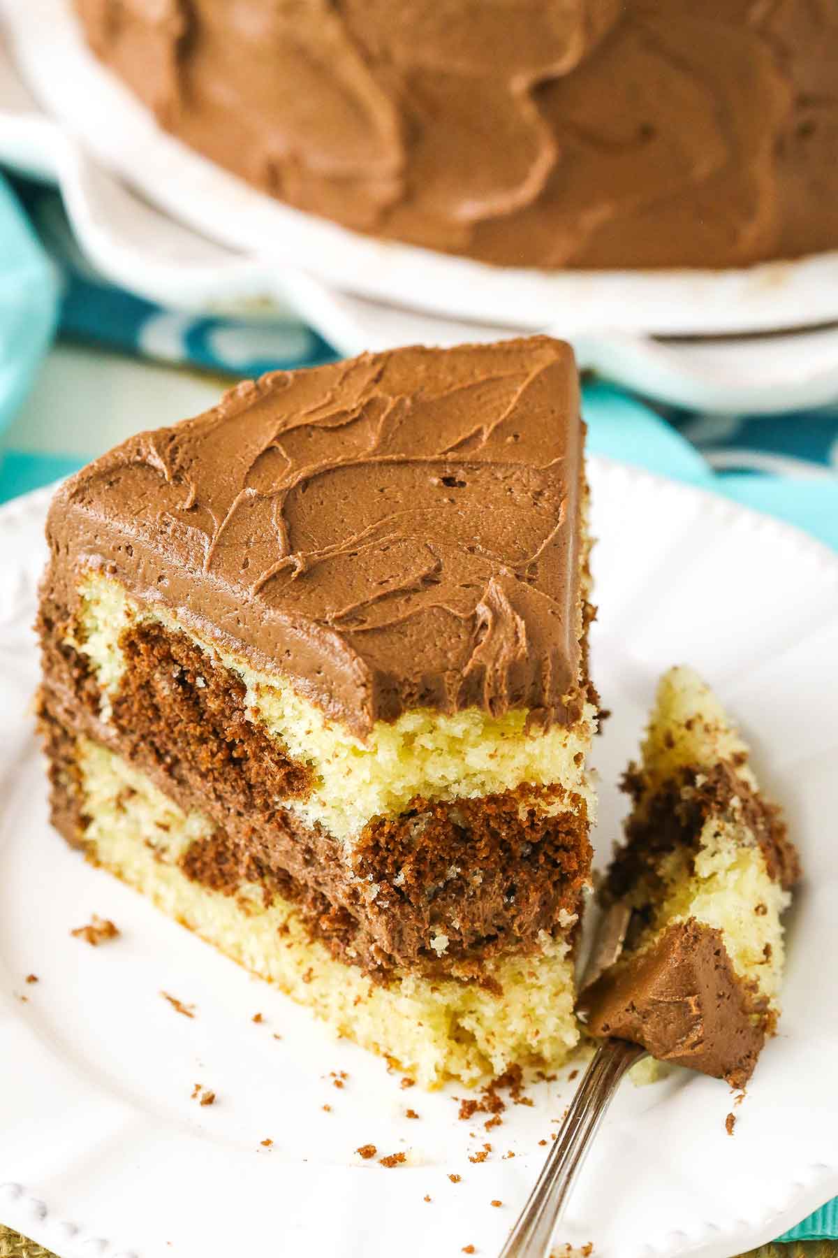 A slice of Marble Cake with a bite removed on a white plate