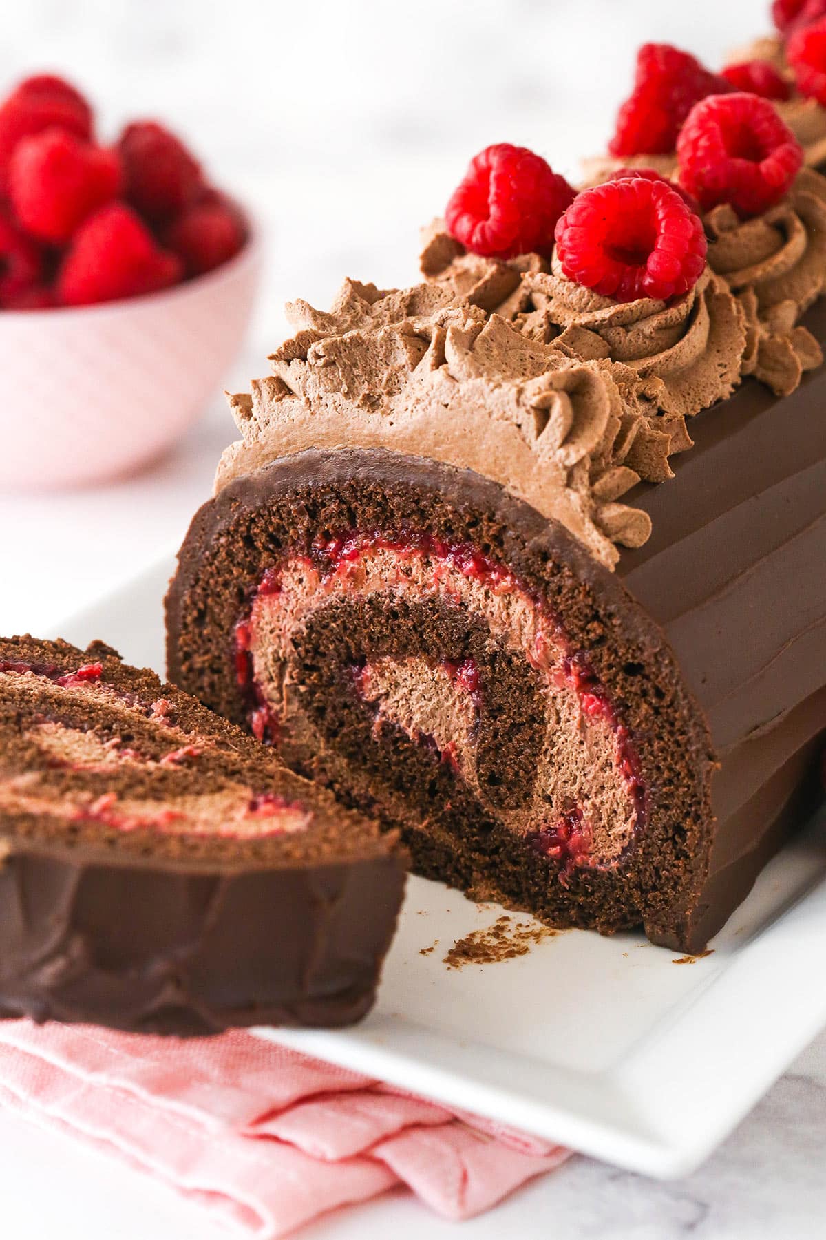 A chocolate raspberry swiss roll with one piece sliced off