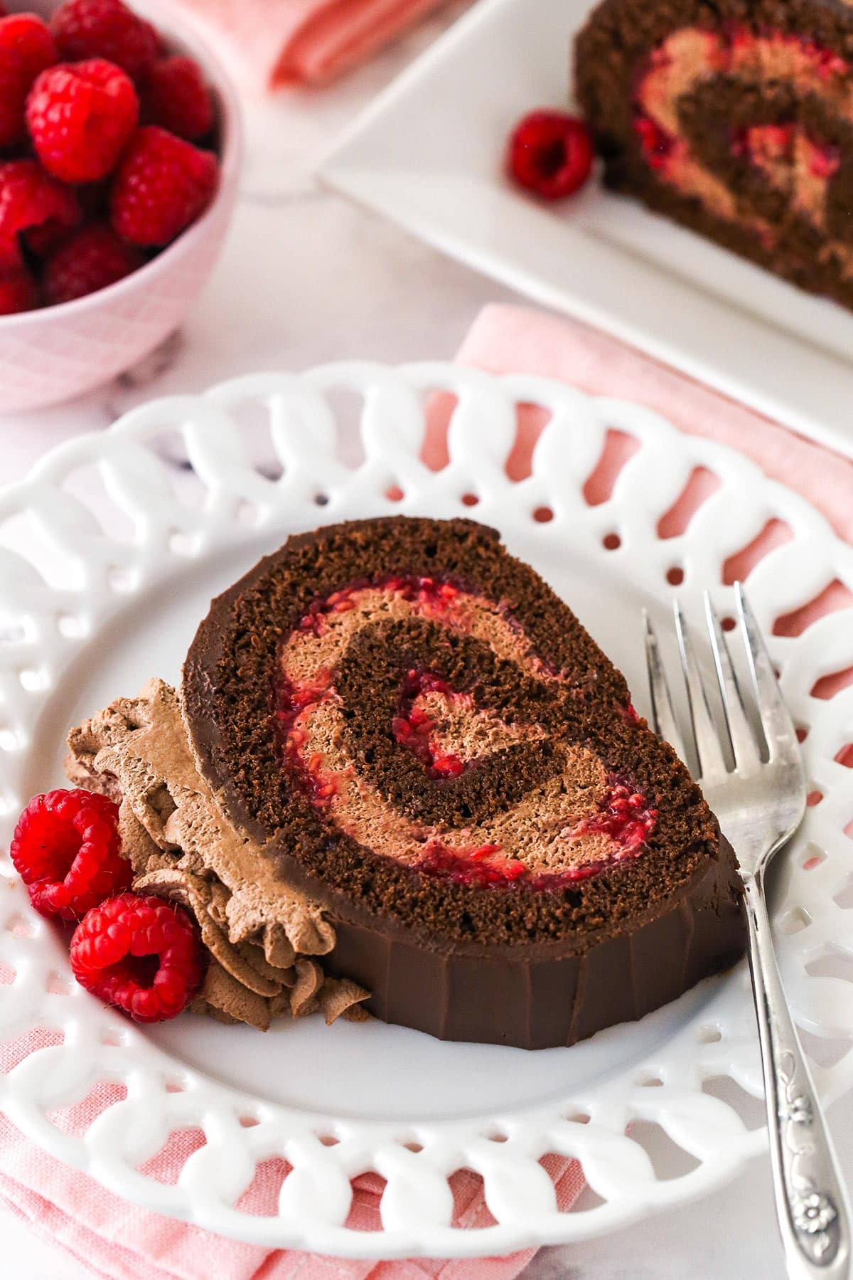 Slice of a raspberry chocolate cake roll on a white plate