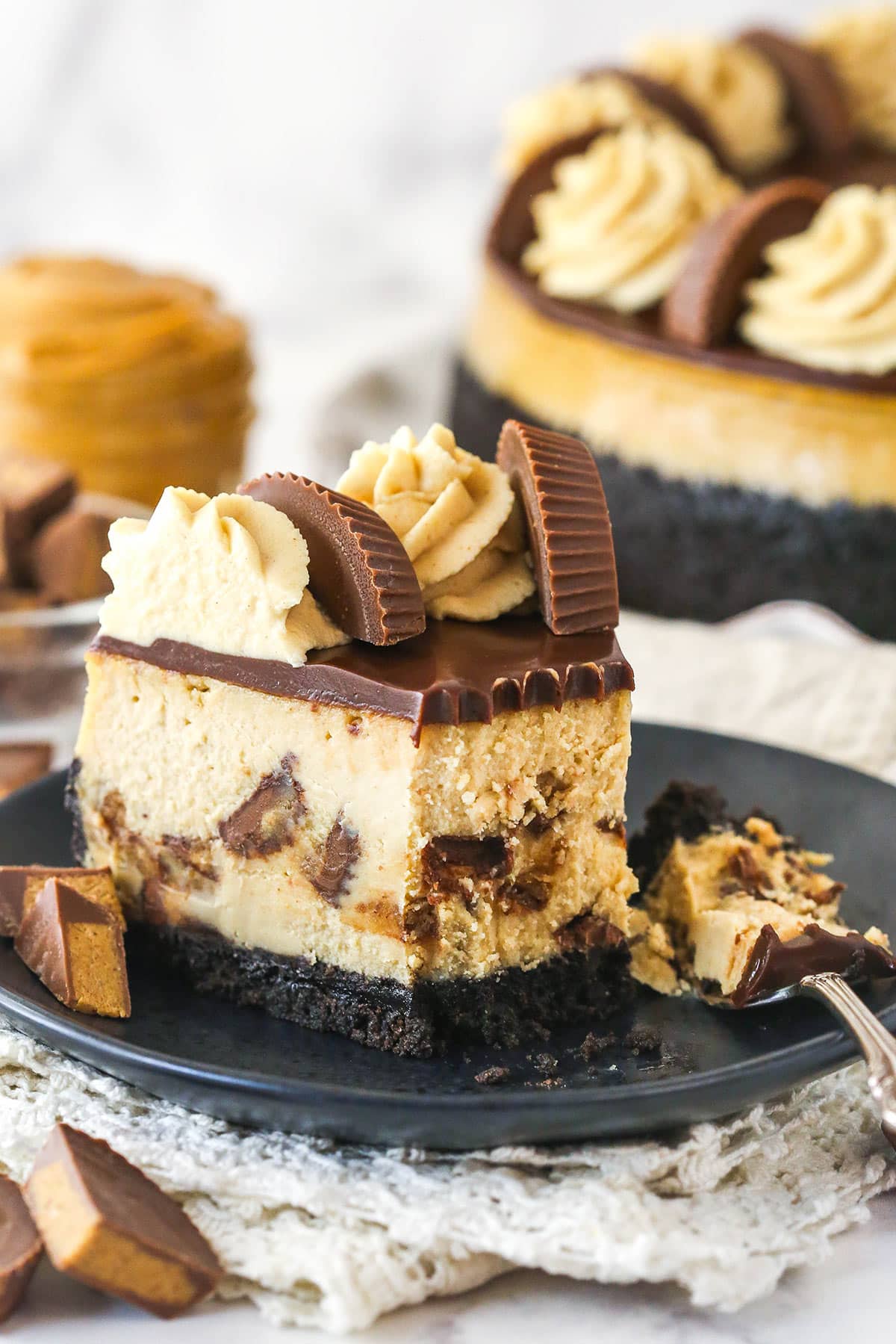 A slice of Reese's cheesecake on a plate with a bite taken.