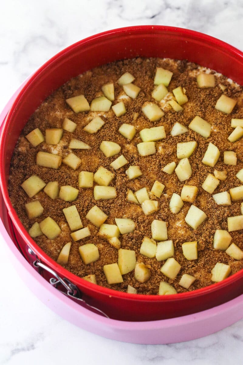 A springform pan prepped for a water bath with layers of cheesecake, apples and cinnamon filling.