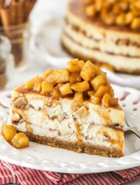 A slice of Apple Cinnamon Cheesecake piled high with apple topping.