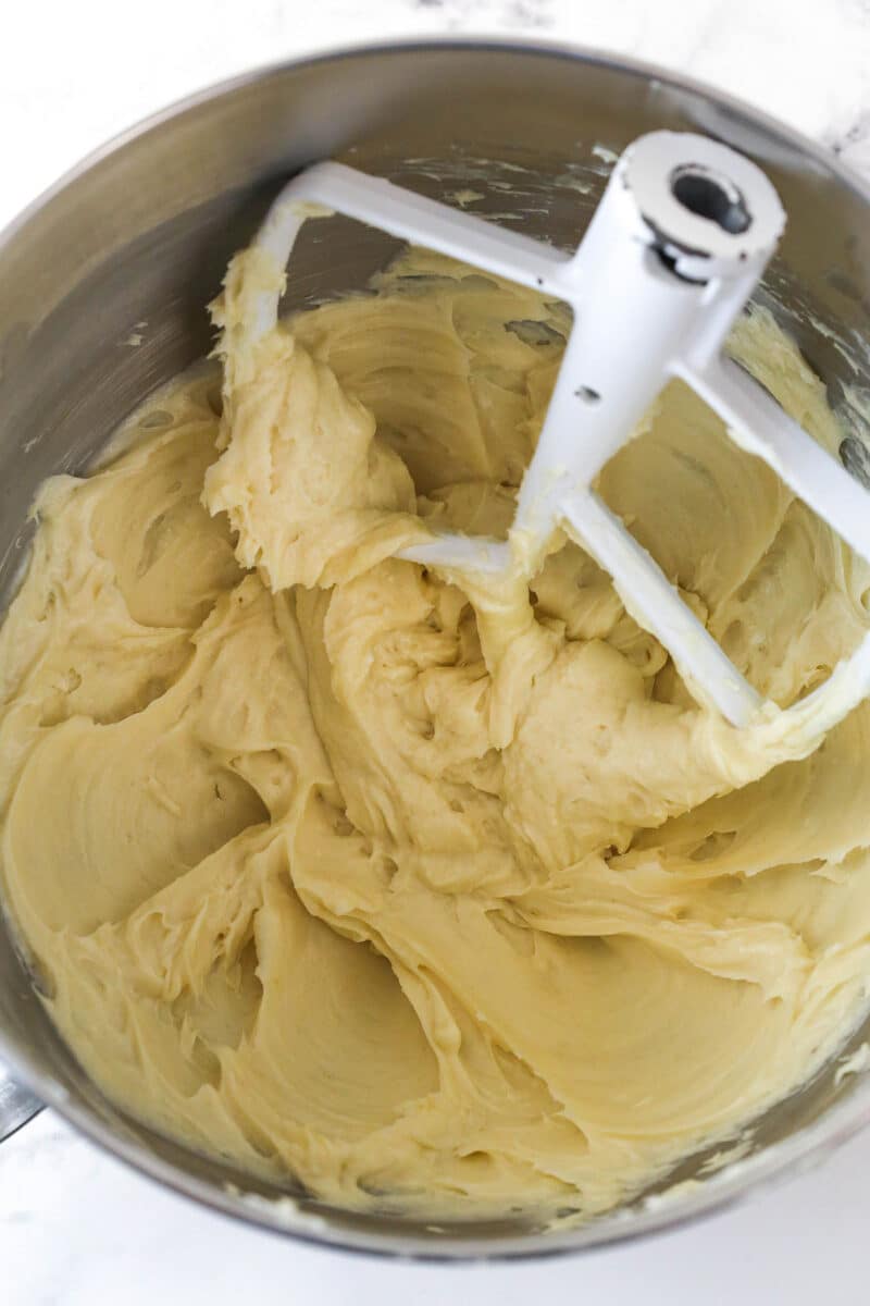 A metal mixing bowl with creamed cream cheese and sugar.