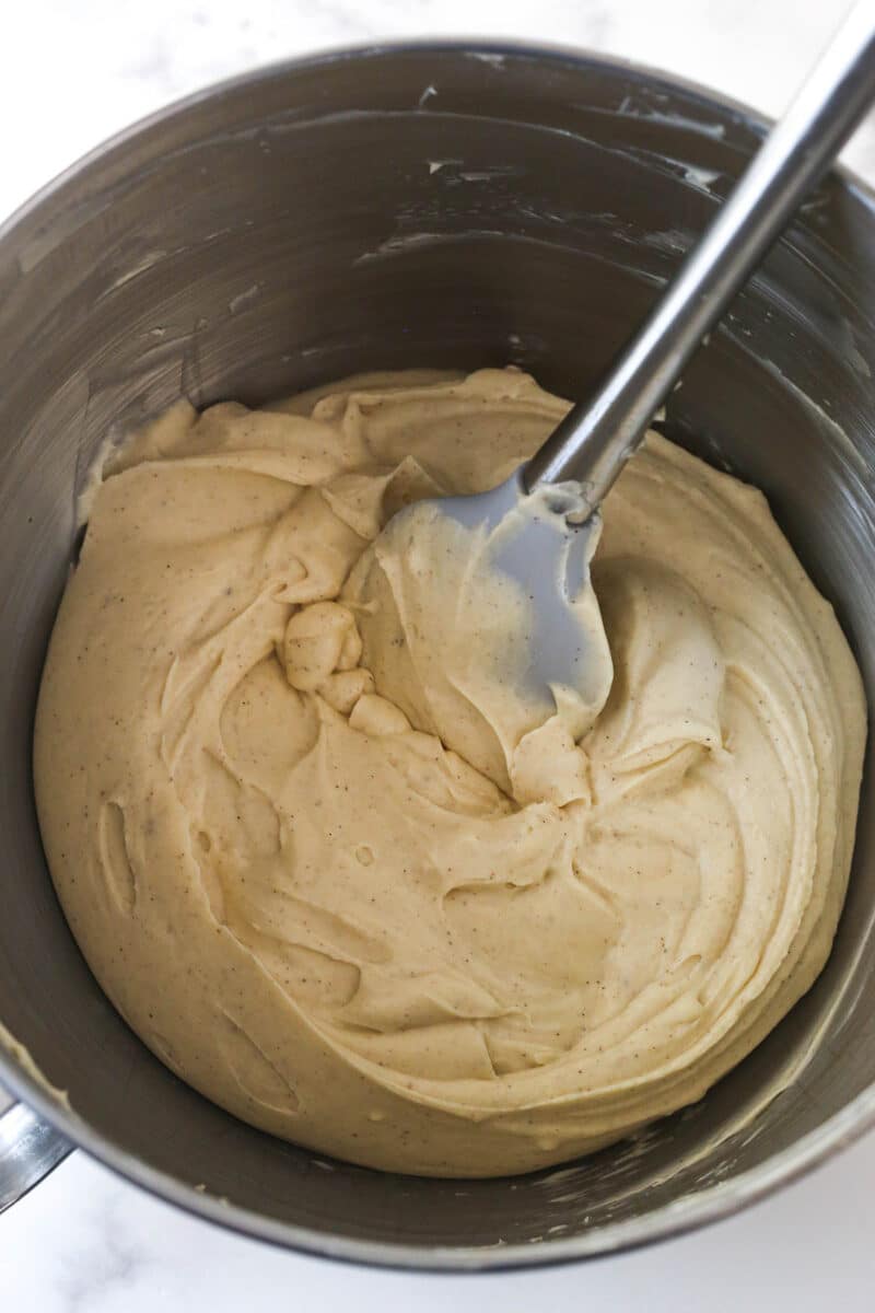 A metal mixing bowl with apple cheesecake filling in it.