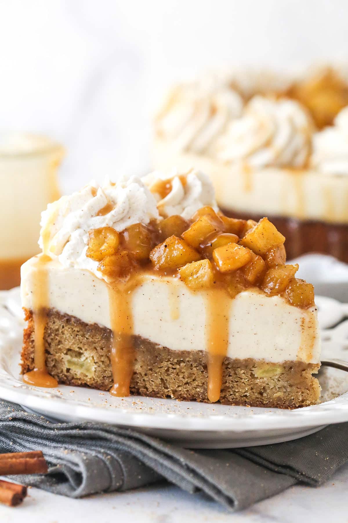 Side view of a slice of Caramel Apple Blondie Cheesecake on a small white plate.