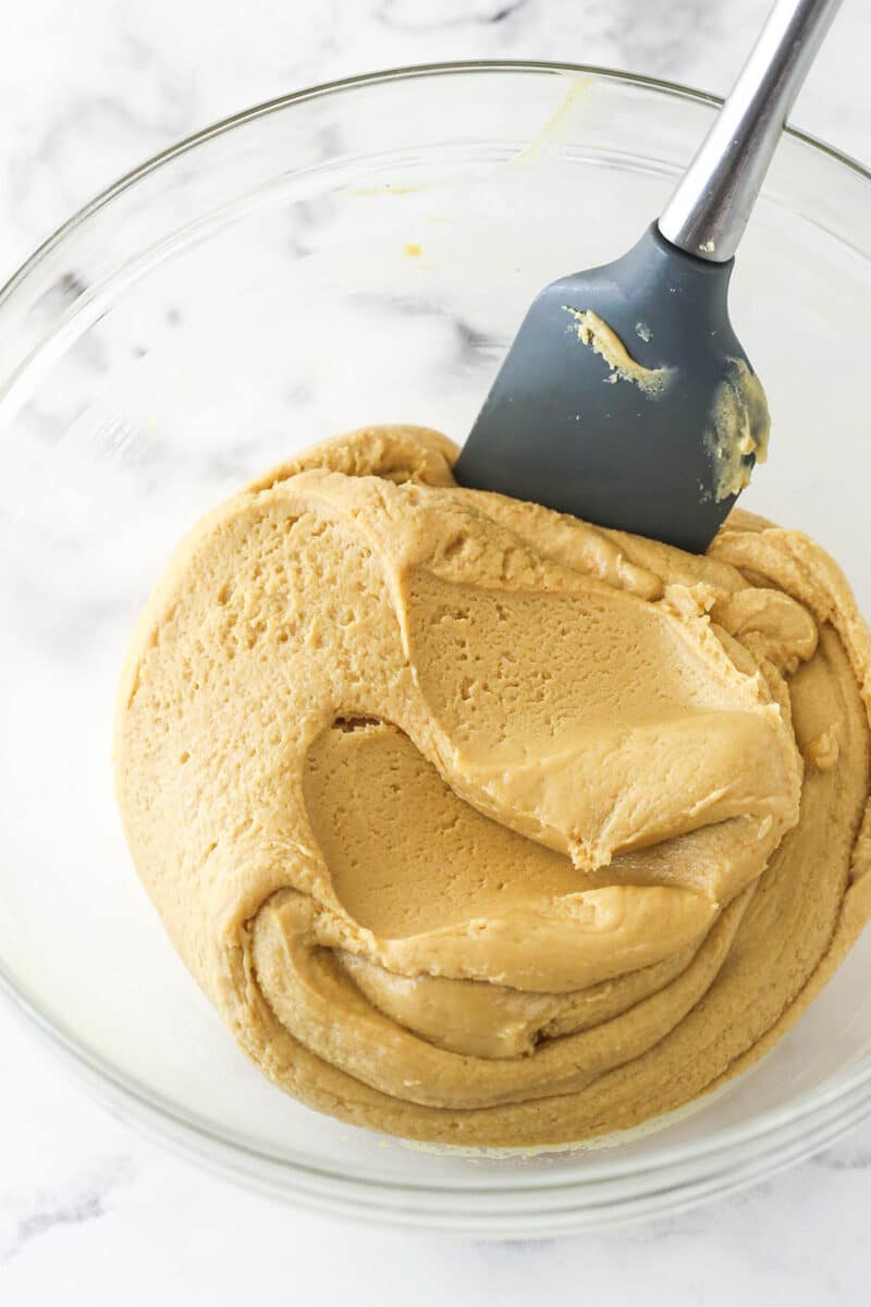 Stirring sweetened condensed milk into melted peanut butter and white chocolate