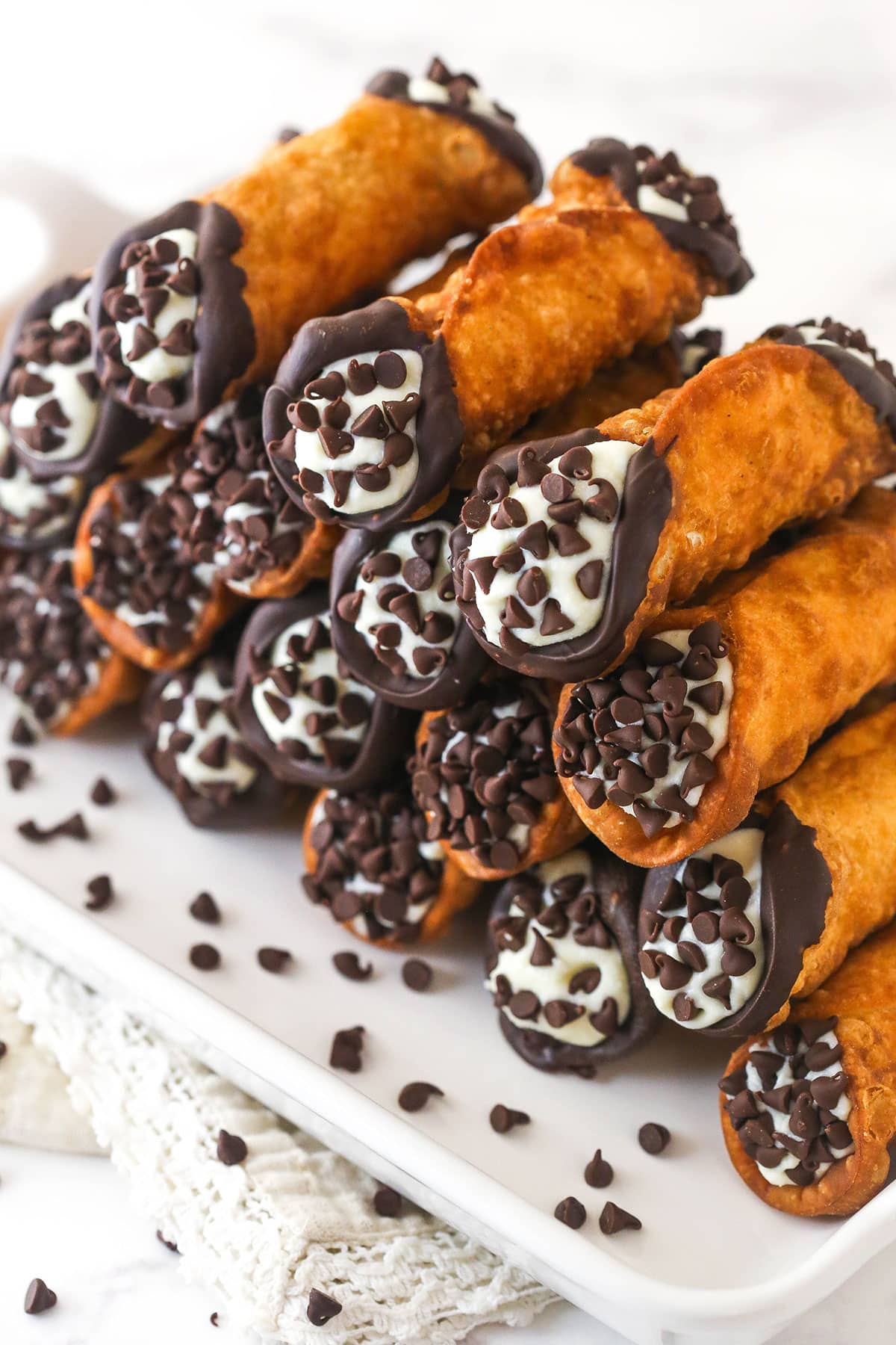 A serving tray of homemade cannoli with chocolate chips