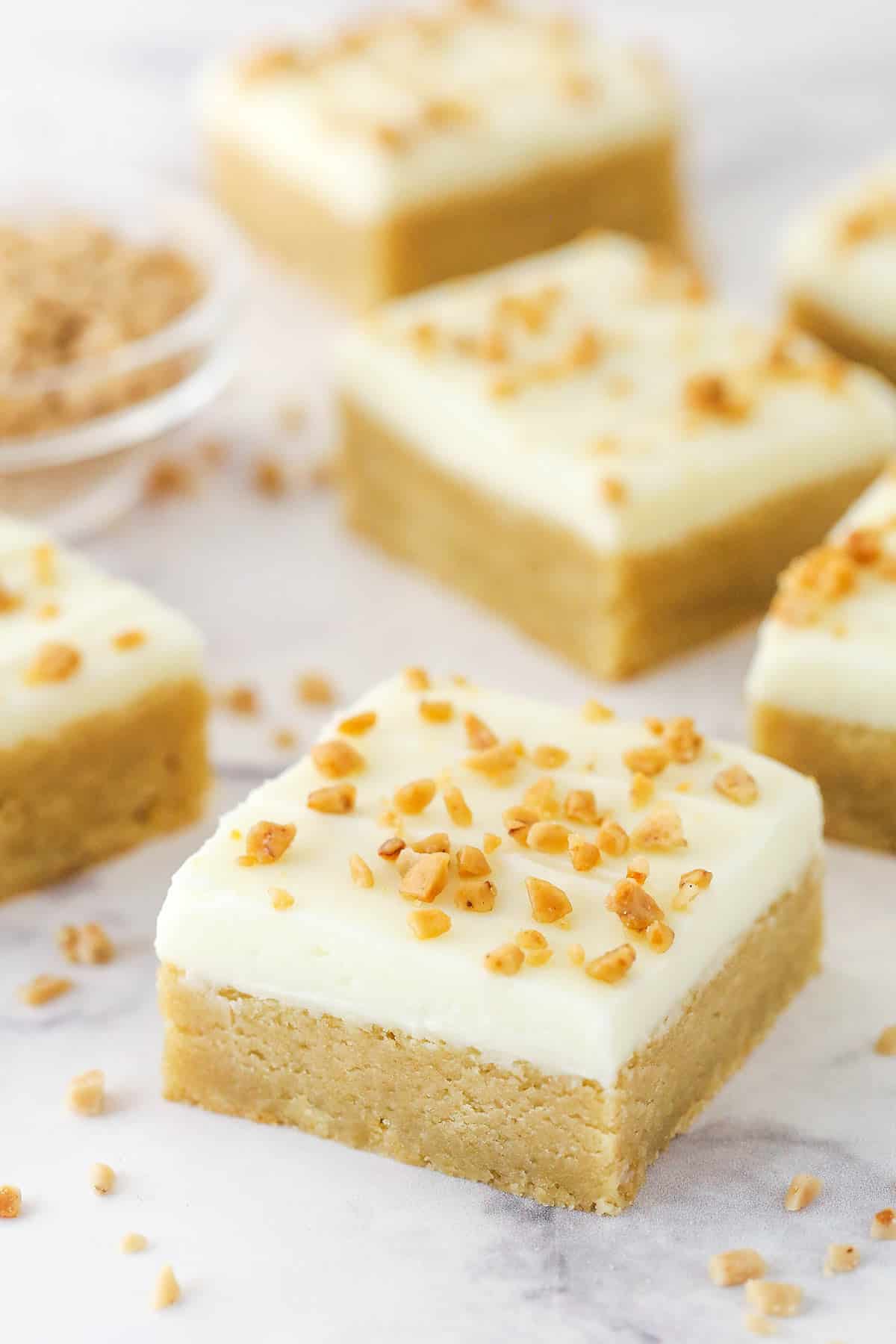 Several Frosted Maple Cookie Bars on a marble surface.