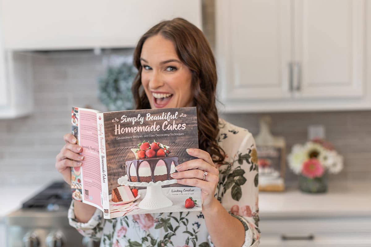 Lindsay in the kitchen holding her cookbook